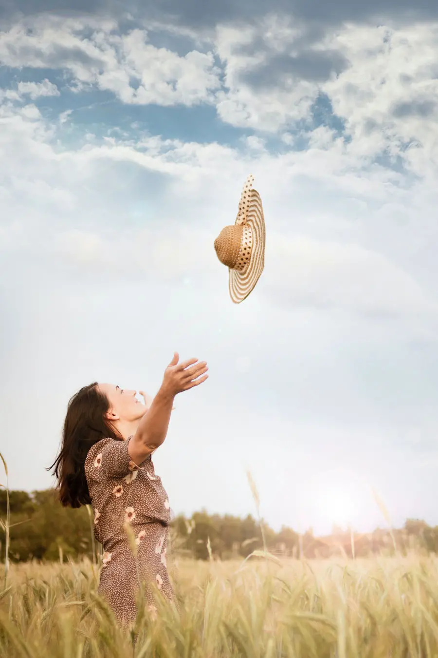 Woman throwing her hat in a meadow